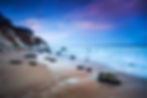 Landschaftsaufnahme Strand und Meer mit Steilküste zur blauen Stunde.