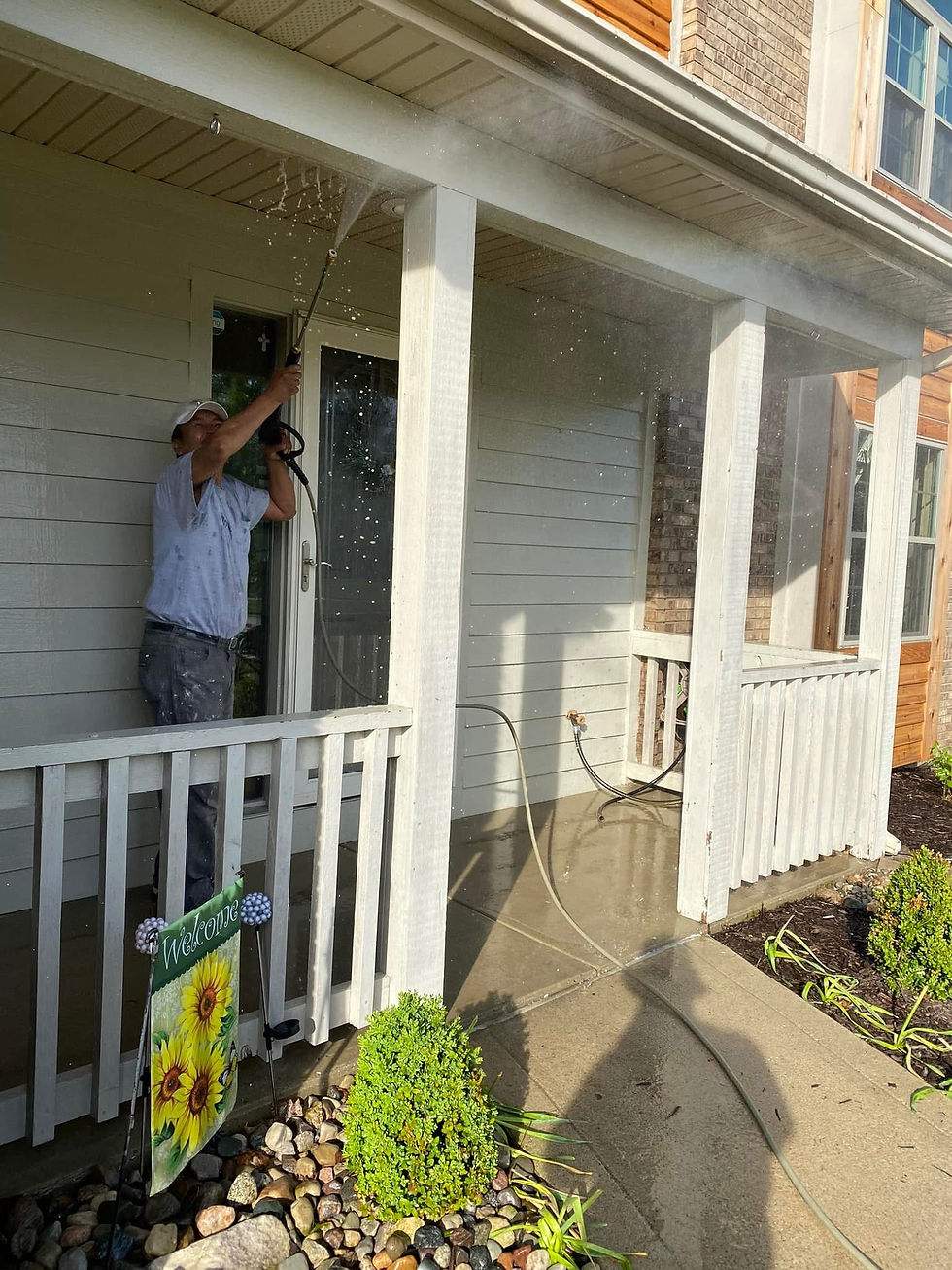 Person power washing the exterior of a light-colored house