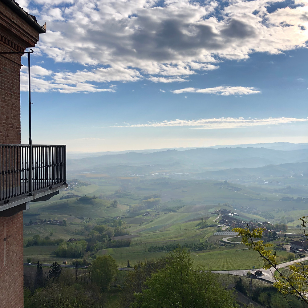 View over the Barolo vineyards from La Morra town centre in the early morning with mist and clouds