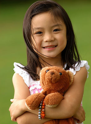 Image of a young Asian girl holding her teddy bear