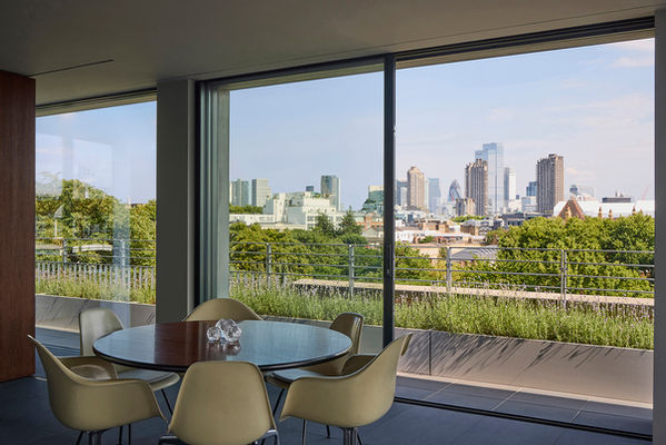 Dining table at Clerkenwell Rooftop, with lavender planting in containers on the wrap-around terrace beyond and the City of London skyline in the distance.