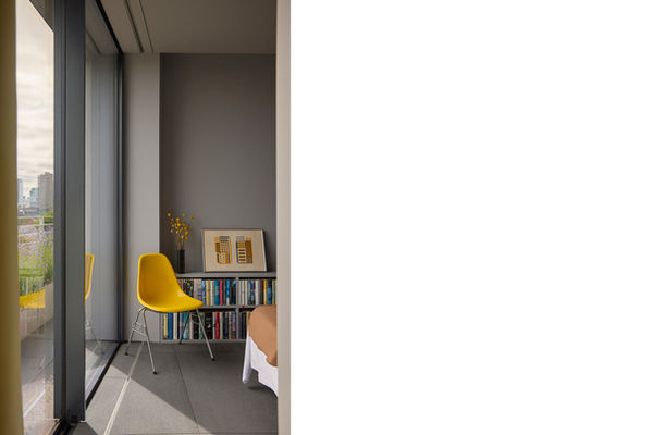 Yellow chair and low-level shelving in the bedroom at Clerkenwell Rooftop, with a glimpse of the wrap-around lavender planting through the full-height glazing to the left.
