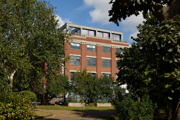 Clerkenwell Rooftop, London, viewed through trees from the adjacent park, with the penthouse situated on a former industrial building.
