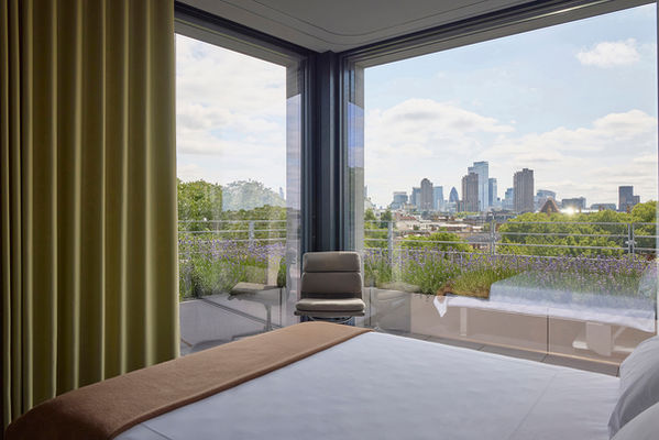 Guest bedroom at Clerkenwell Rooftop, configured on the other side of the timber-clad monolith, with the bed folded down from within and the City of London skyline beyond.