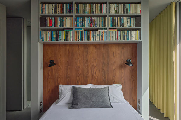 A view of Bed at Clerkenwell Rooftop, recessed beneath high-level bookshelves with a timber headboard.