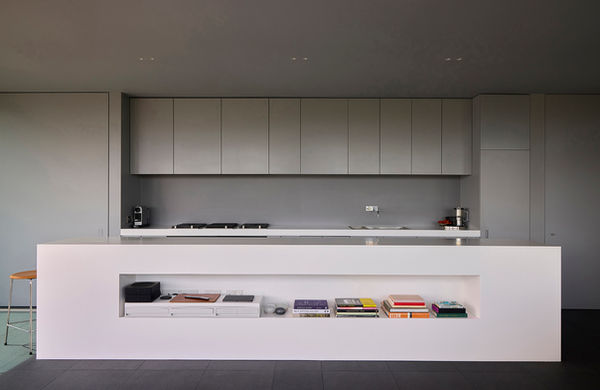 White corian-clad kitchen island at Clerkenwell Rooftop, with a shelf recessed into the long side facing the open-plan living space.