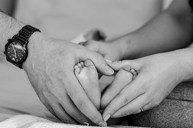 Newborn baby's feet in a heart shape with Mum and Dad's hands