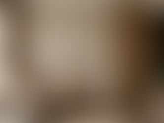 A detailed interior photograph showcasing a contemporary Singapore living room renovation by Cosmos Decor, embodying the 2026 'Tactile Luxury' trend. The space features a seamless blend of textured materials, including a warm beige limewash feature wall and vertical solid wood fluted panels. A plush, cream-colored bouclé armchair with a terracotta accent cushion is paired with a raw travertine stone side table holding dried pampas grass. Soft, filtered sunlight streams through sheer linen curtains, highlighting the natural textures and creating a serene sensory sanctuary. This design illustrates Cosmos Decor's expertise in creating grounded, wellness-focused homes in Singapore.