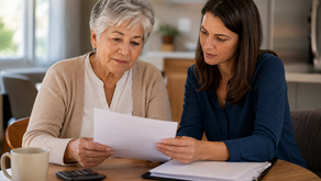 Older woman and adult daughter reviewing financial paperwork together at a kitchen table.