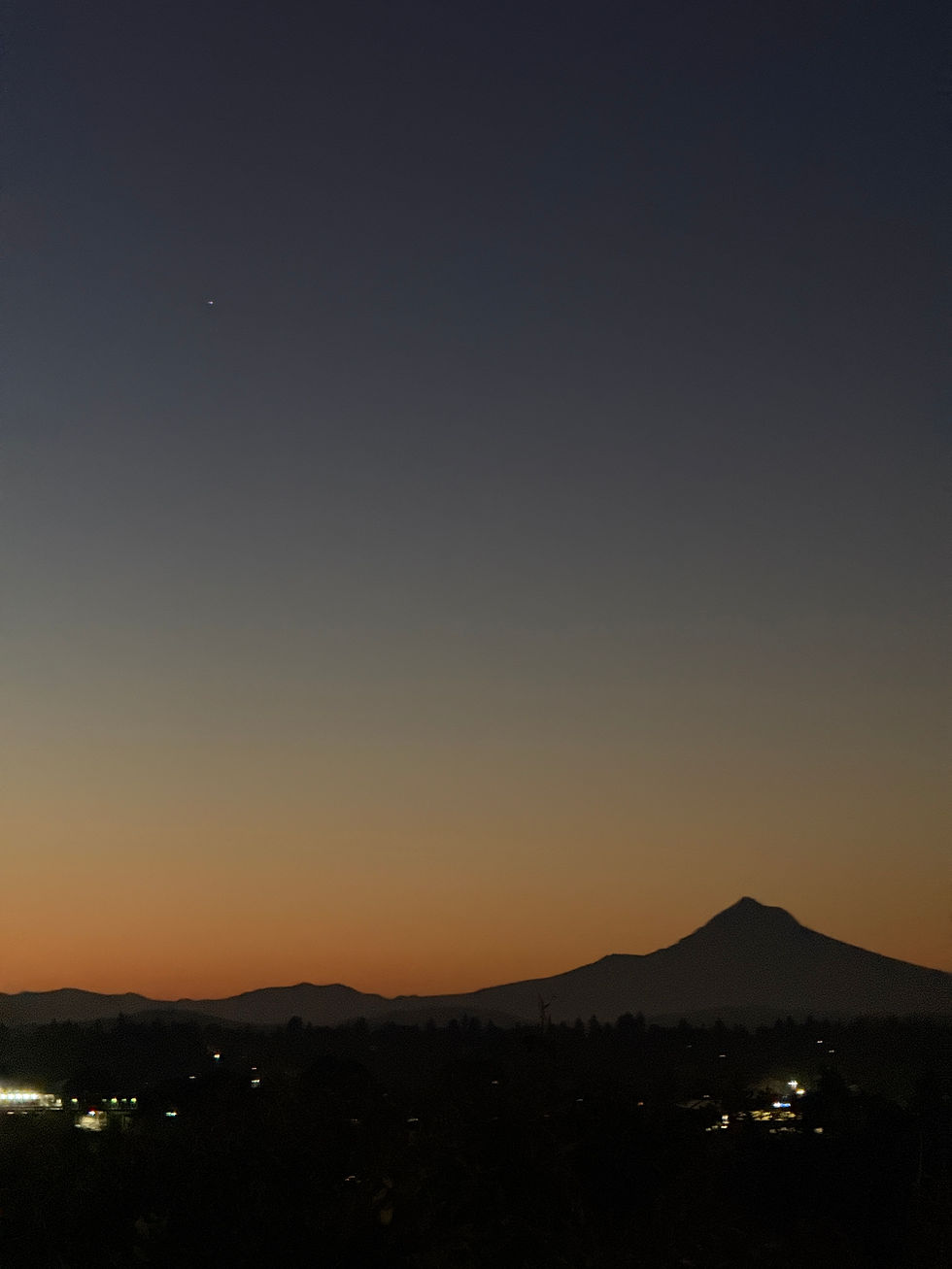 Mountain silhouette at twilight with distant town lights