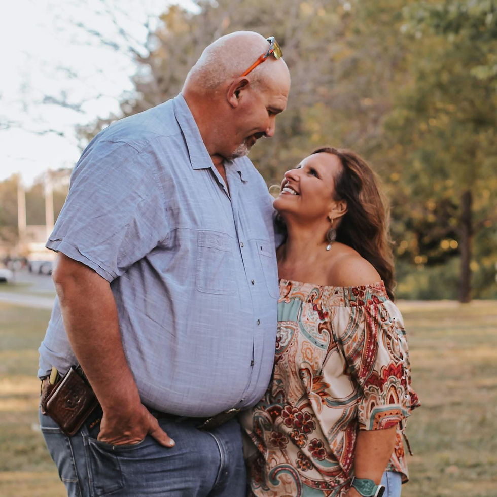 Man and woman smiling, looking at each other outdoors affectionately.