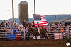 Rodeo rider on horseback carrying American flag