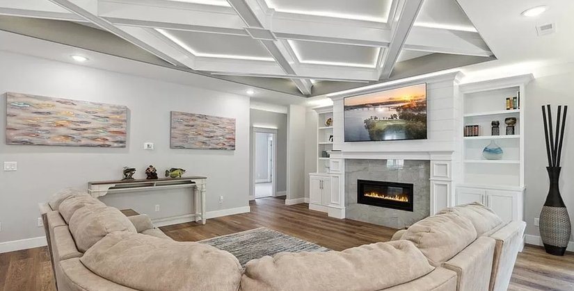 Elegant living room with custom ceiling design, LED lighting, and a built-in entertainment center with modern fireplace.