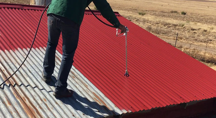 A man painting a metal roof