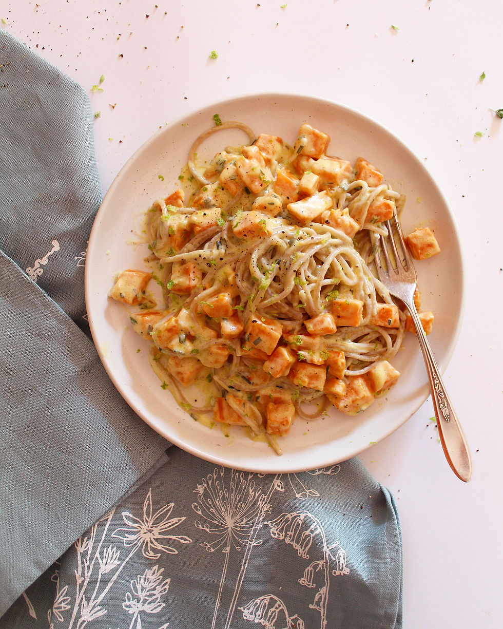 Creamy pumpkin coconut pasta with chives, served on a white plate with a fork — a cozy, dairy-free seasonal meal made with real, wholesome ingredients.