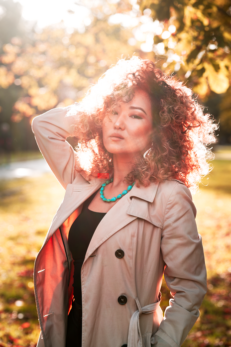 Portrait of dazzling girl with curly hair with sun shining on her face in background at london