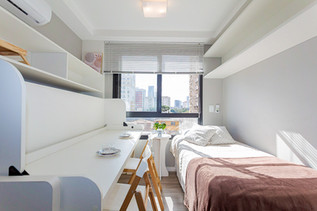 quarto de um airbnb em curitiba, com um mesa, com pires  postos, há grande incidência solar, fotografia profissional realizada para anuncio de airbnb.