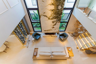 vista superior de uma bela sala em que há uma lareira que vai até o teto, a lareira é em mármore branco, fotografia profissional de imóveis.