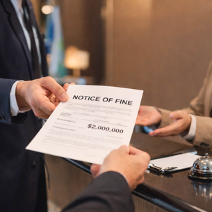 A hotel worker being handed a notice of a fine paper.