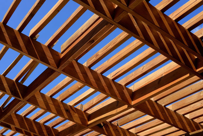 Overhead view of a custom-built wooden pergola casting shadows against a blue sky