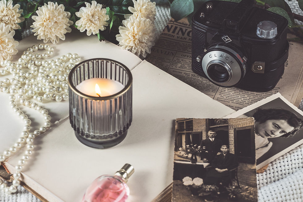 memorial table with candle, perfume, beads, camera, flowers and photographs of a loved one