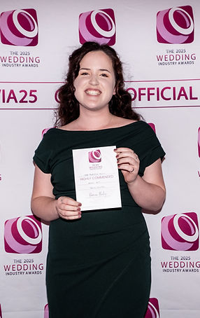 A woman holding a certificate that says 'Highly Commended' in a a green dress.