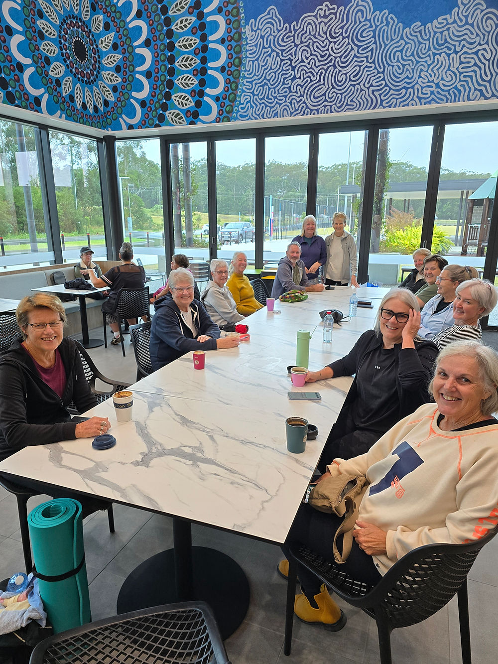 Clients enjoying coffee at the Wiigulga cafe after class, with Tulli Stevens' artwork displayed in the background