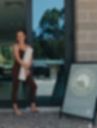 One of the teaching team standing outside Woopi Pilates & Yoga in Woolgoolga, next to the A-frame sign, ready to welcome clients to the mat