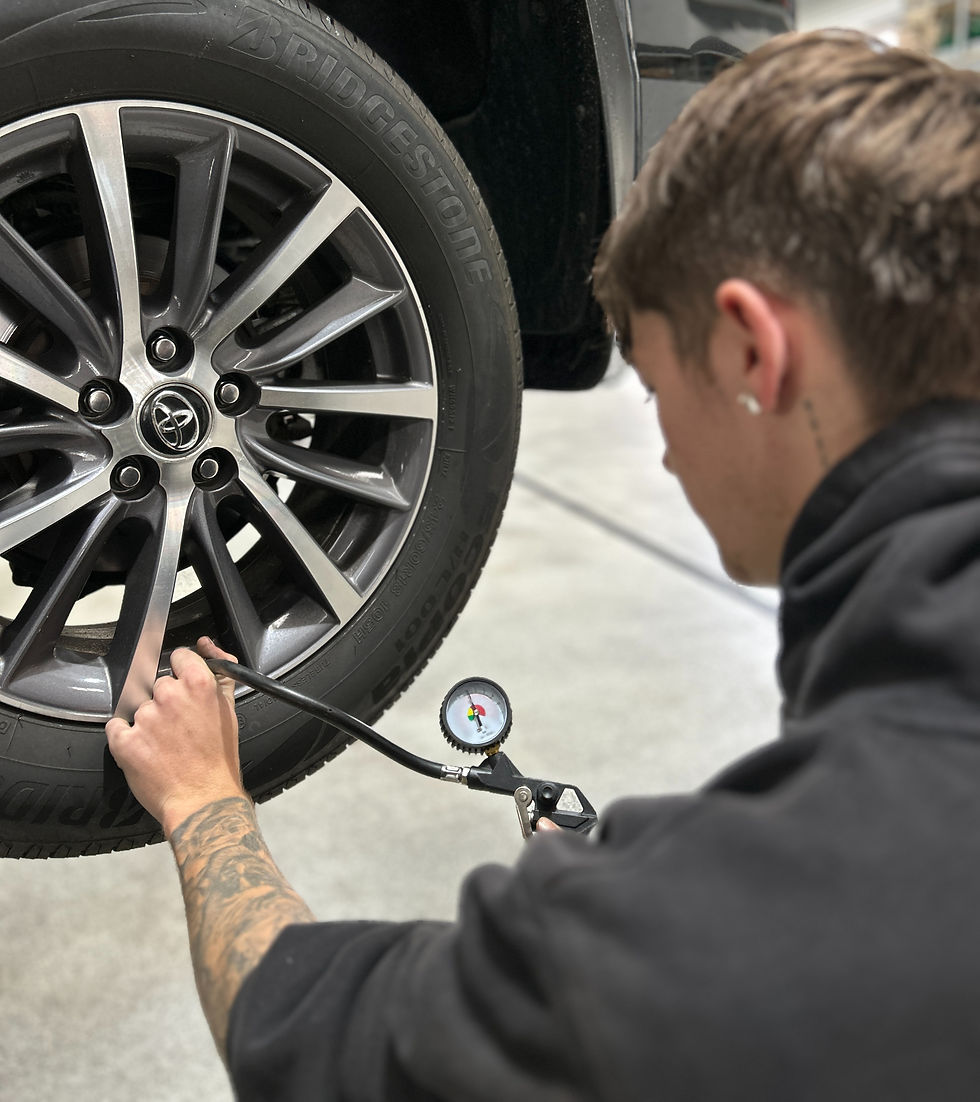 A mechanic uses a tyre gauge to check tyre pressure