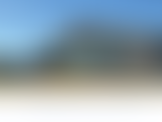 Exterior view of the nearly completed Rayburn Electric Co Op Recreational Facility in Rockwall, Texas, showing the modern facade with large windows, stone base, and finished parking area under a bright blue sky.