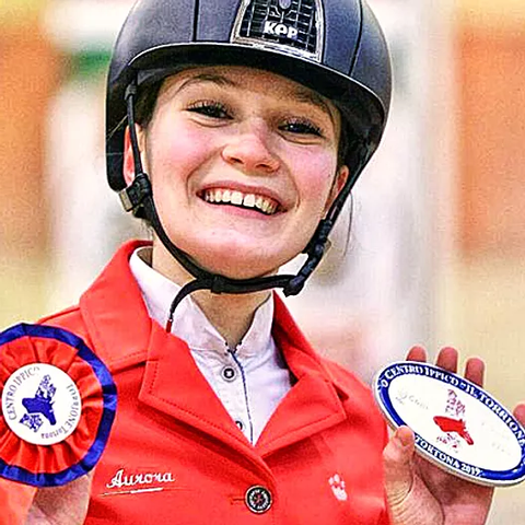 LoveHorses è orgogliosa di presentare Aurora Pace, un amazzone dalle incredibili abilità e dal sorriso contagioso. In questa foto, Aurora si mostra radiosa di felicità con le coccarde in mano
La sua passione per l'equitazione e l'amore per gli animali sono evidenti nel suo sorriso. Aurora è una vera icona di LoveHorses, ispirando appassionati di equitazione in tutto il mondo.