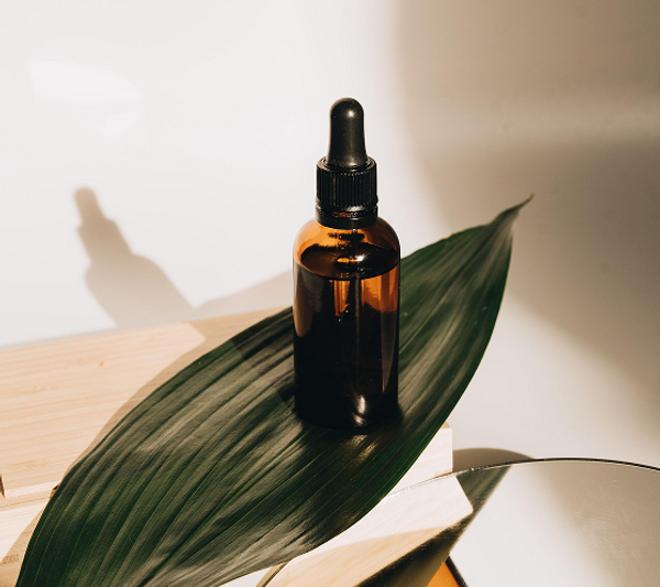 Amber botanical wellness bottle surrounded by green leaves.png