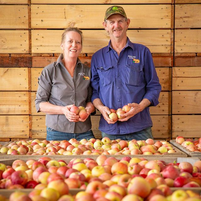 Kaye and Michael Fox standing in front of box of apples