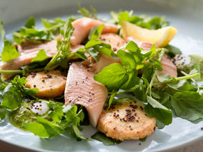 A fresh salad featuring flaked hot smoked trout, vibrant watercress, and small golden shortbread biscuits, adding a buttery crunch to the dish. The salad is plated simply, highlighting texture and contrast.