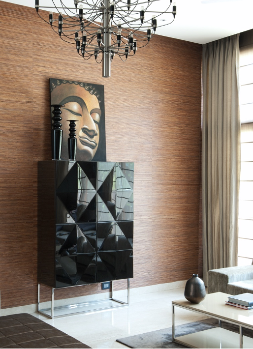 Tall cabinet with Art placed on top. Wallpaper in the background. Contemporary chandelier.