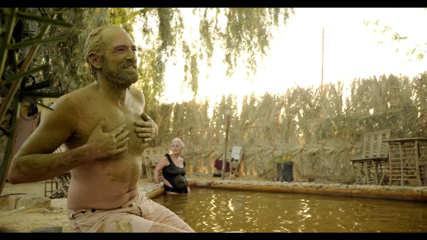A man covers his face and body with green mud at Al Maza Hot Spring in Siwa, Egypt on Sauna Channel.