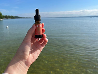 A bottle of organic CBD oil held out over the lake in northern Michigan