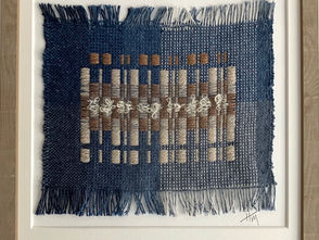 Handwoven textile art, natural and sand colour geometric squares, tactile wool boucle, handwoven against an ombre blue background, framed in natural wood frame