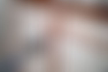 Person painting a metal fence with red paint and brush.