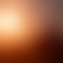 Silhouette of a person using a laptop on grass at sunset. Warm orange sky sets a calm mood. No text visible.