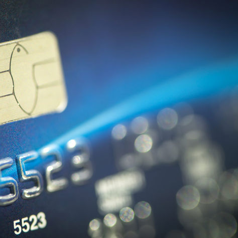 Close-up of a blue credit card chip with embossed numbers 5523, in a soft-focus macro shot.