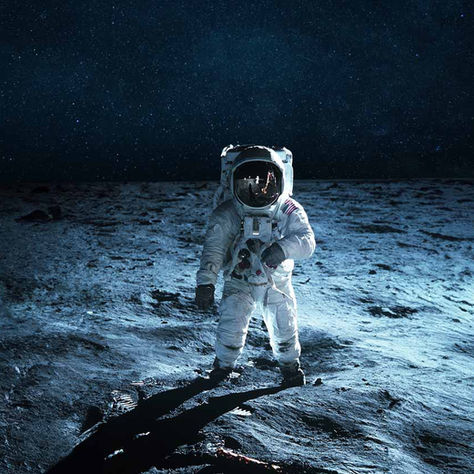 Astronaut on the moon, standing in a white suit with starry sky in the background. Lunar surface is barren and shadowy, creating a serene mood.