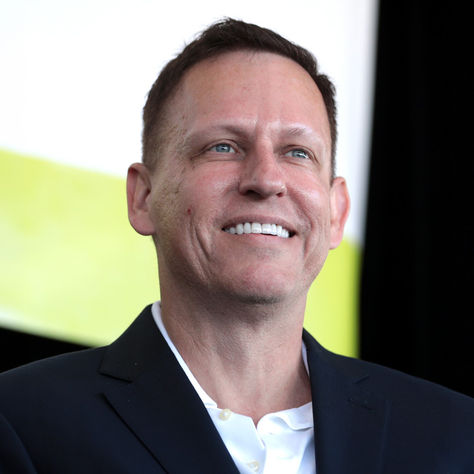 Smiling man in a dark suit onstage against a lime-green and black backdrop