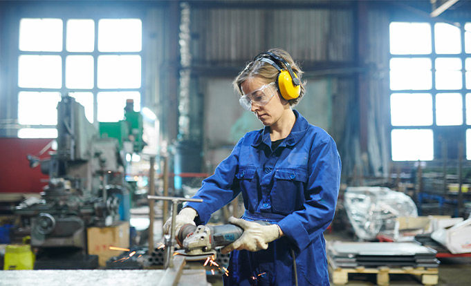 Potrait of modern female worker cutting metal at industrial plant or garage