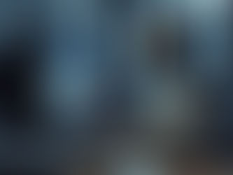 Humanoid robot types at a desktop computer in a modern office, with a blurred coworker in the background.