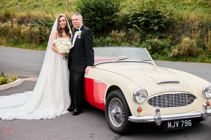Bride and groom with a classic car at their wedding