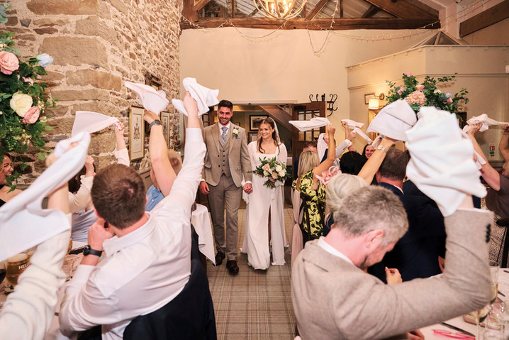 Guests wave napkins as bride and groom enter wedding reception