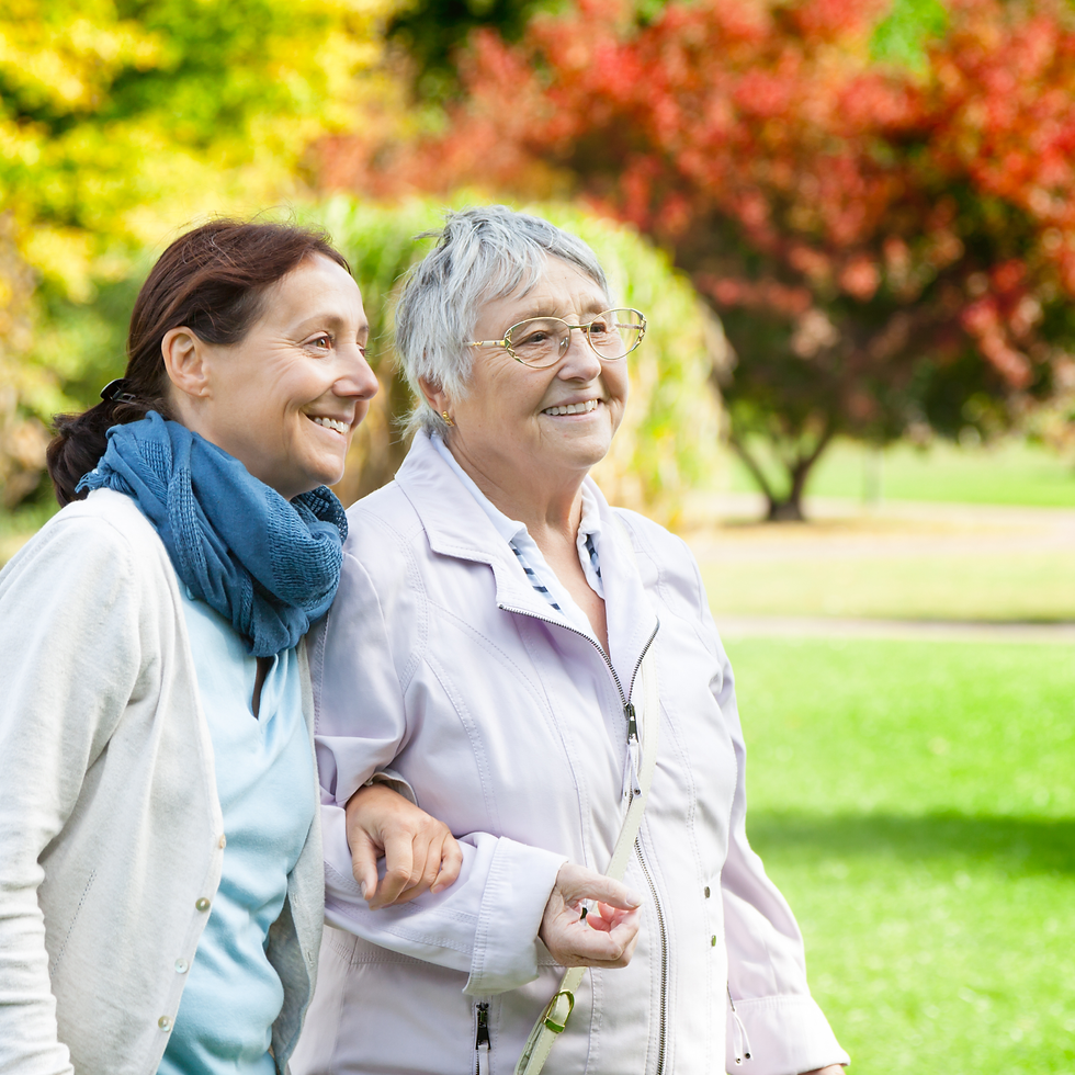 Two women walk down a serene path in the fall, arms linked.