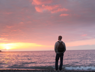 A man looking at a sunset on the beach.