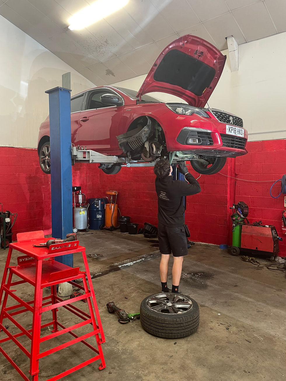 Mechanic working on a lifted red car in a workshop